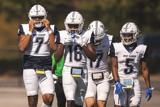 Four football players walking the sideline together after a game