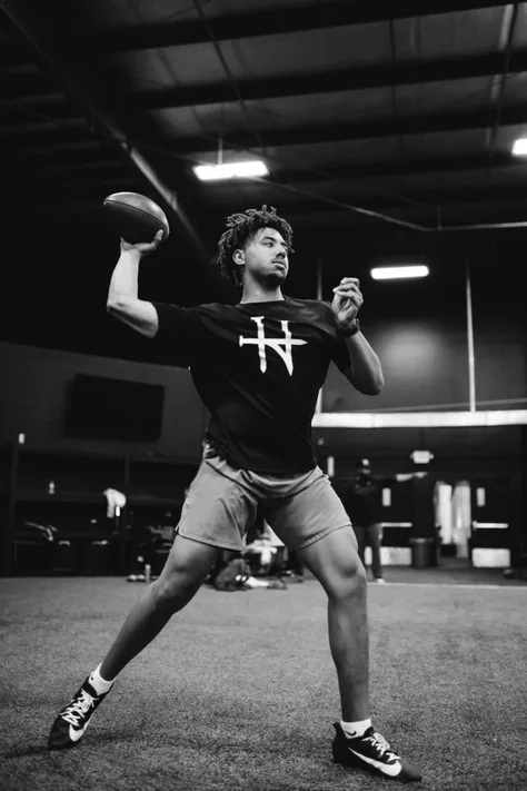 Quarterback mid-throw on indoor turf, arm cocked and ready to deliver