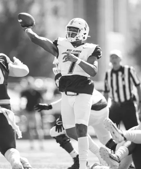 Quarterback in the pocket ready to throw with a defender closing in